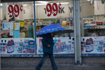  ?? AP Photo/DAmIAn DoVArgAnEs ?? A pedestrian walks past a 99-Cents store under light rain in Los Angeles on Wednesday.