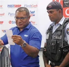  ??  ?? Post Fiji head of retail and marketing Isaac Mow announcing one of the winners of Post Fiji’s Back to School promotion, with a Police OFfiCER OVERSEEING THE PROCESS.