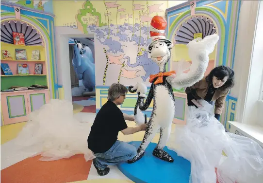  ?? PHOTOS: STEVEN SENNE/THE ASSOCIATED PRESS ?? John and Kay Simpson unwrap a statue of the Cat in the Hat at the new Amazing World of Dr. Seuss museum in Springfiel­d, Mass.