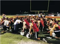  ?? JOE SKIPPER / THE ASSOCIATED PRESS ?? Members of the Marjory Stoneman Douglas High School football team pray together as they began practice for a new season just after midnight on Monday.