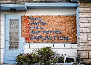  ?? BRUCE R. BENNETT / THE PALM BEACH POST ?? A Lake Worth home lists storm items — and a warning — on a plywood covering Thursday. Many residents will heed officials’ calls and remain in their homes during the hurricane.