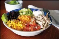  ?? PHOTO BY EMILY RYAN ?? Brown rice forms the base of this burrito bowl, featuring chicken, avocado, black beans, corn, fresh salsa, cheese and sour cream.