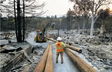  ?? Paul Kuroda / Special to The Chronicle ?? PG&E workers maneuver utility poles in a scorched section of Glen Ellen as the utility works to restore power in fire areas.