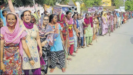  ?? MANOJ DHAKA/HT ?? Devotees carrying sticks gathered in front of the Dera Sacha Sauda gates ‘to protect the premises’ in Sirsa on Thursday.