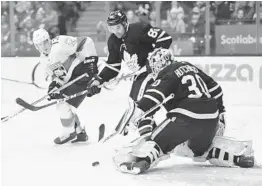  ?? FRANK GUNN/AP ?? Maple Leafs goaltender Michael Hutchinson makes a save as Panthers defenseman Mark Pysyk and Maple Leafs defenseman Cody Ceci eye the rebound Monday in Toronto.