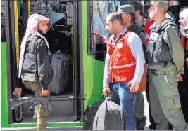  ?? SANA VIA THE ASSOCIATED PRESS ?? An anti-Syrian government fighter, left, carries his machine gun and looks at a Syrian policeman as he leaves the last besieged rebel-held neighborho­od of Al-Waer in Homs province, Syria, on Monday. Syria said a cease-fire brokered by the U.S. and...