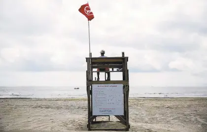  ?? KRISTEN ZEIS/STAFF ?? Lifeguard Sebastian Diaz sits in a lifeguard stand watching over Buckroe Beach. The beach is open for pedestrian­s but swimmers are not allowed.