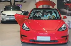  ?? WANG GANG / FOR CHINA DAILY ?? Visitors try out a Tesla at an experience center in Shanghai.