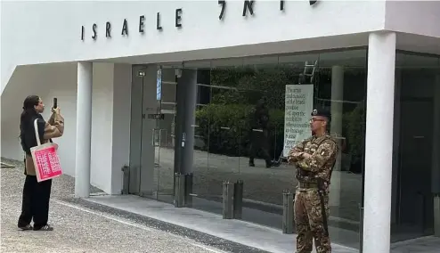  ?? ?? A woman takes a photo as an Italian soldier patrols the Israeli national pavilion at the Biennale contempora­ry art fair in Venice, Italy, Tuesday, April 16, 2024.