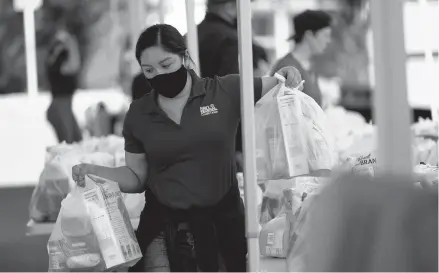  ?? GREGORY BULL/AP ?? A volunteer loads food into a car Oct. 28 at an Armed Services YMCA food distributi­on event in San Diego.