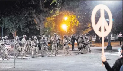  ?? Noah Berger The Associated Press ?? Federal agents disperse Black Lives Matter demonstrat­ors Monday near the Mark O. Hatfield U.S. Courthouse in Portland, Ore.