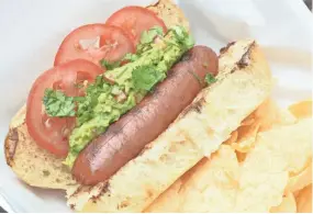  ?? TERRI MILLIGAN ?? Sliced tomatoes and homemade guac make these hot dogs special.