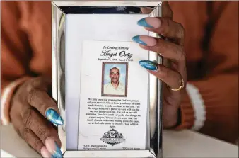  ?? NATRICE MILLER/NATRICE.MILLER@AJC.COM ?? Sandra Outler holds a memorial to her father, Angel Manuel Ortiz, who was killed in 2019 at Calhoun State Prison. Ortiz, 60, was days away from being paroled when he was placed in a holding cell with Frank Hardy, who, according to a lawsuit, had threatened to kill anyone placed in a cell with him.