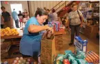  ??  ?? Margie Paninski, 54, loads a shopping bag full of donated groceries for flood survivor Dawn Hay, 40, right, at South Walker Baptist Church in Walker, La.