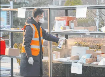  ?? Ren Chao Xinhua News Agency ?? A staff member disinfects parcels mailed from overseas Tuesday at a community under restrictio­ns where a locally transmitte­d COVID-19 case was found in Beijing.