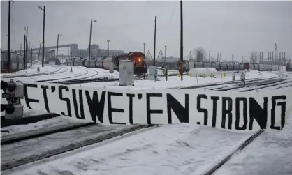  ?? Photograph: Christinne Muschi/Reuters ?? A CN train sits on the tracks behind a sign placed by supporters of the Wet’suwet’en Nation at a blockade in Montreal on 2 March.
