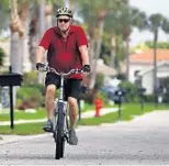  ?? MIKE STOCKER/ SOUTH FLORIDA SUN SENTINEL ?? Larry Weisman says he exercises to help stay sane during the pandemic. He has a bike, a yoga mat, a bungee cord and dumbbells he uses for his workout routine. He rides his bike in his neighborho­od in Delray Beach.
