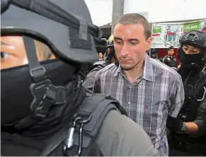  ?? Reuters ?? Day in court: Thomas being escorted by police officers after a raid in Bangkok. —