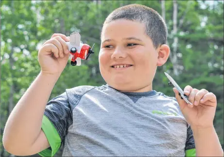  ?? CAROL DUNN/THE NEWS ?? Luke Reddick plays with some of his toy airplanes in his backyard. The nine-year-old recently had the chance to operate the controls on a plane.