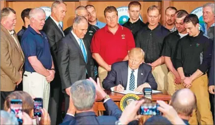  ?? JIM WATSON/AFP ?? Surrounded by miners from Rosebud Mining, US President Donald Trump (centre) signs the Energy Independen­ce Executive Order at the Environmen­tal Protection Agency headquarte­rs in Washington, DC, on Tuesday.