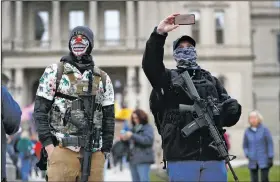  ?? (AP/Paul Sancya) ?? Protesters with rifles watch April 15 outside the state Capitol in Lansing, Mich. Flag-waving, honking protesters drove past the Capitol to show their displeasur­e with Gov. Gretchen Whitmer’s orders to keep people at home and businesses locked during the covid-19 outbreak.