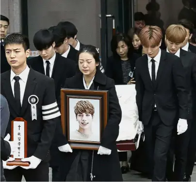  ??  ?? Sorrowful send-off: Members of SHINee carrying Kim’s coffin as Kim’s sister holds a picture of him during his funeral in Seoul. — AP