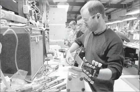  ?? Christophe­r Berkey For The Times ?? LOREN AMSBARY adjusts a guitar at Gibson’s Nashville plant last year. Some retailers have stopped selling the brand, citing unmanageab­le demands. “The company is in the worst place I’ve ever seen it in my decades as a dealer,” said a shop owner in...
