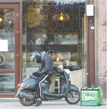  ?? VALENTYN OGIRENKO/REUTERS ?? An Uber Eats food delivery courier waits for an order in front of a restaurant, which was closed as a measure to prevent the spread of COVID-19 in Kyiv, Ukraine, on Wednesday.