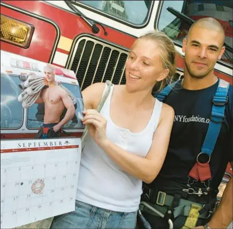  ?? ?? Rosie Byars, a tourist from London, looks mighty pleased at the Big Apple’s eye candy as she views Firefighte­r Rick Gonzales in the 2007 Calendar of Heroes as Gonzales looks on. Now the FDNY Foundation is discontinu­ing the calendar, citing declining interest.