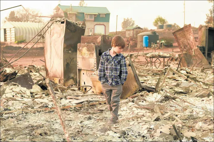  ?? JOSH EDELSON/GETTY-AFP ?? Jacob Saylors, 11, walks through the burned remains of his home in Paradise, Calif., on Nov. 18. The family lost a home in the same spot to a fire 10 years prior.