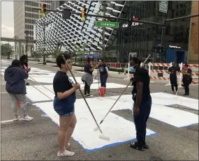  ?? ED WHITE—ASSOCIATED PRESS ?? Students from University Prep Art Design celebrate Juneteenth by repainting a street mural, “Power To The People,” in downtown Detroit on Saturday, June 19, 2021.