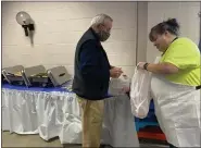  ?? ?? Gerald Nowotarski of Oley packs up a take-out pork and sauerkraut meal with the help of Kim Bless of Fleetwood, a volunteer at the pork and sauerkraut fundraiser at Ruscombman­or Volunteer Fire Company on New Year’s Day 2022.