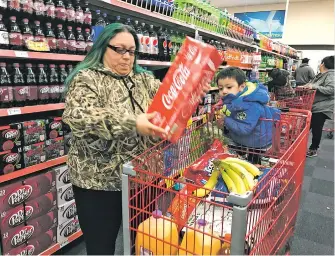  ?? DANIEL J. CHACÓN THE NEW MEXICAN ?? Julie Sanchez of Española loads Coca-Cola into her cart Thursday at the Food King on St. Michael’s Drive. Sanchez, who shops for groceries in Santa Fe, says a proposed tax on sugary beverages would change her buying habits, forcing her to buy healthier...