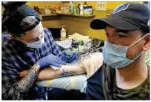 ?? MARSHALL GORBY / STAFF ?? Robert Lamb of Truth and Triumph Tattoo works on the tattoo of Tyler Milligan. Friday was the first day for tattoo shops to open since March.