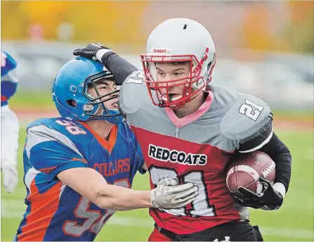 ?? BOB TYMCZYSZYN
THE ST. CATHARINES STANDARD ?? Governor Simcoe’s Danny Lewis (21) is grabbed by Welland Centennial's Mitch Hingley (58) in semifinal high school football.