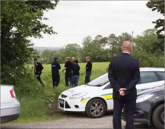  ??  ?? Local detectives and uniformed gardai gather at a field between Blackwater and Kilmuckrid­ge last Wednesday following the discovery of a shallow grave with human remains.