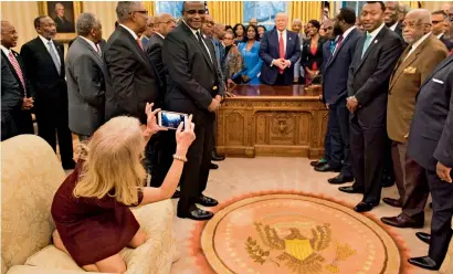  ?? AFP ?? Kellyanne Conway takes a photo as President Trump and leading educators talk in the Oval Office of the White House. —