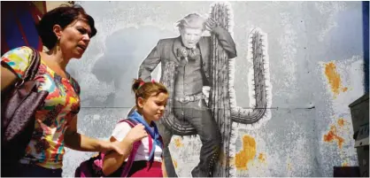  ??  ?? HAVANA: A woman walks with her daughter past a mural painting depicting US President Donald Trump. — AP