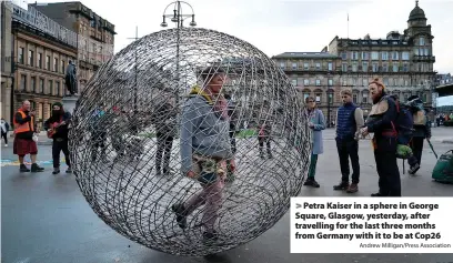  ?? Andrew Milligan/Press Associatio­n ?? > Petra Kaiser in a sphere in George Square, Glasgow, yesterday, after travelling for the last three months from Germany with it to be at Cop26