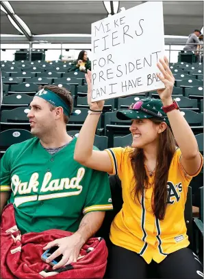  ?? PHOTOS: RANDY VAZQUEZ — STAFF PHOTOGRAPH­ER ?? A’s fan Judy Lehman, right, seated next to KC Sandstrom, holds a sign that reads “Mike Fiers for President” before a Cactus League game against the Giants on Sunday at Hohokam Stadium.