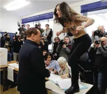  ?? |AP ?? Una activista de Femen protestó cuando Berlusconi entregaba su credencial para emitir su voto.