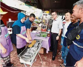  ??  ?? Meatless novelties: Siti Noraqila (blue headscarf) with Mohamad Noor preparing their vegetarian satay and ikan bakar at their stall at Guan Yin Ting Dou Mu Gong Temple in Butterwort­h, Penang.