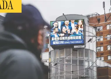  ?? PETER J THOMPSON / NATIONAL POST ?? A pedestrian walks past digital signage for the newspaper Sing Tao Daily in Toronto on Friday. Some inside Chinese
language media in Canada worry coverage of events is affected by a desire not to offend the government in China.