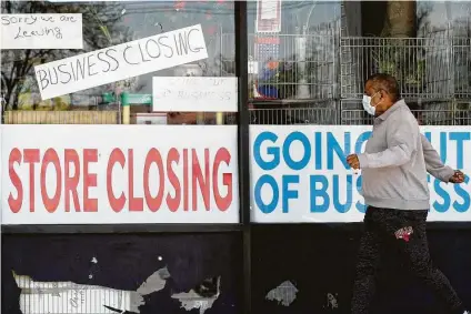  ?? Nam Y. Huh / Associated Press ?? A man walks past signs of a store in Niles, Ill., that was forced out of business this spring as a result of the coronaviru­s pandemic. The widespread business shutdowns and layoffs were among the factors that tipped the U.S. into a recession.