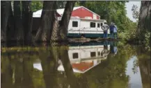  ?? ?? Neighbors look at a backyard Friday after it was damaged by severe flooding in Fromberg, Mont.