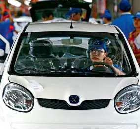  ??  ?? Des ouvriers testent le système d’éclairage d’un véhicule Jiangling utilisant de nouvelles sources d’énergie.