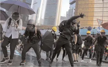  ?? —AP ?? An anti-government protester throws a rock near Central Government Complex in Hong Kong on Sunday.