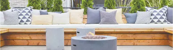  ??  ?? A gorgeous propane-fed fire pit that doubles as a barbecue for cookouts is the focal point for this built-in wraparound bench adorned with a myriad of throw pillows.
