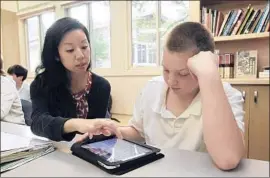  ?? Gary Reyes MCT ?? TEACHER Christina Pak, left, helps Chase Kerley use his iPad in 2010. Students can take the National Assessment of Educationa­l Progress test on tablets.