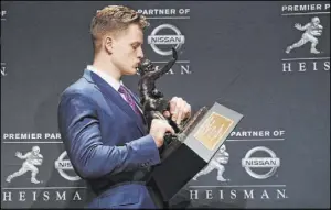  ?? Jason Szenes The Associated Press ?? Louisiana State quarterbac­k Joe Burrow kisses his Heisman Trophy.